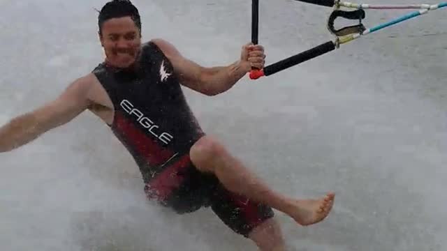 Barefoot waterskiing guy wipe out after tricks
