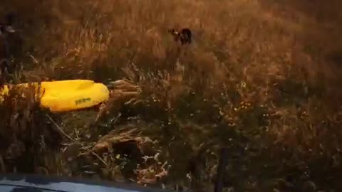 Two guys being pulled behind truck on yellow kayak