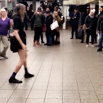 Older woman in purple dances to music in subway station