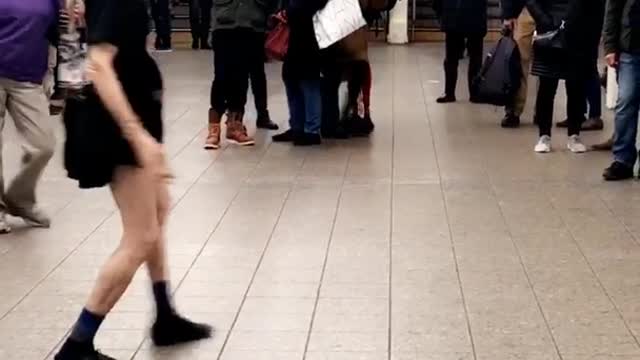 Older woman in purple dances to music in subway station