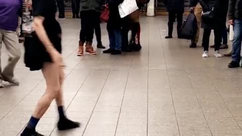 Older woman in purple dances to music in subway station