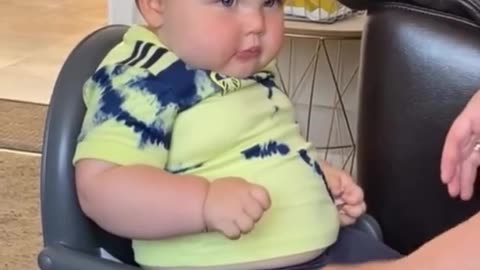 Fat funny baby strapping himself in his baby seat