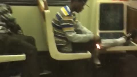 Guy on subway train lights something on fire and holds it to leg