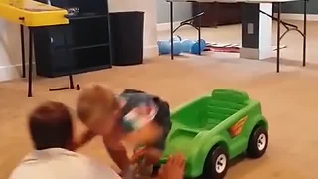 Baby riding tiny plastic car runs into guy and they bump heads