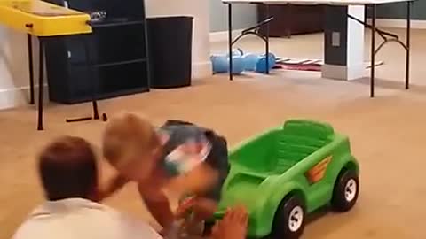 Baby riding tiny plastic car runs into guy and they bump heads