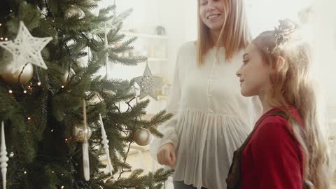 Girl near the Christmas tree with her mother