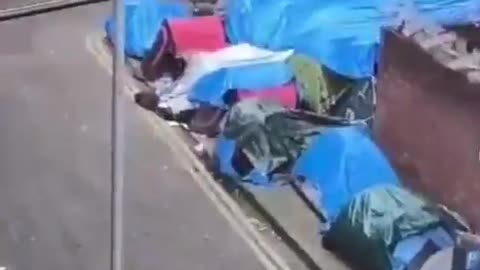 A woman living beside the open-air migrant camp in Dublin reacts to portable