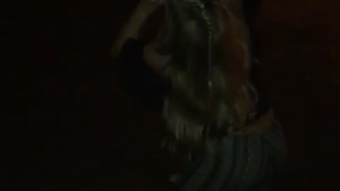 Music blonde girl in green pants chugs three beers outside at night