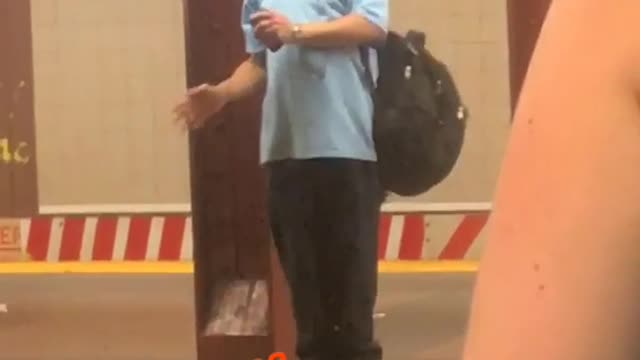 Man in blue shirt dancing on subway platform