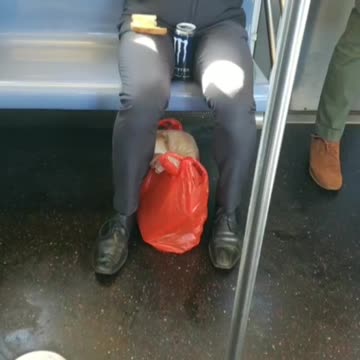 Guy eating eggs out of a bowl with toast on a subway train