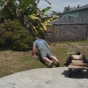 Man belly surfs on grass backyard
