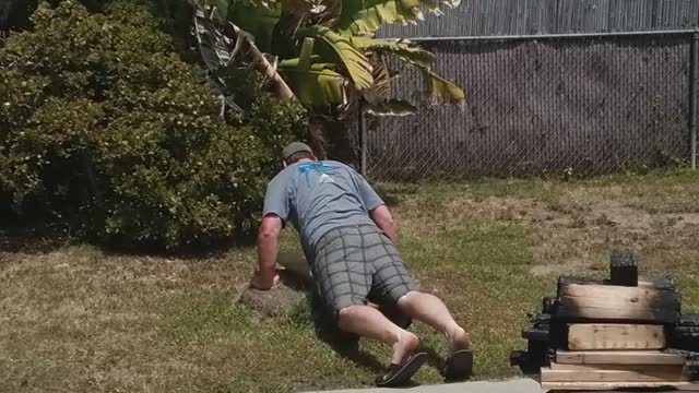 Man belly surfs on grass backyard