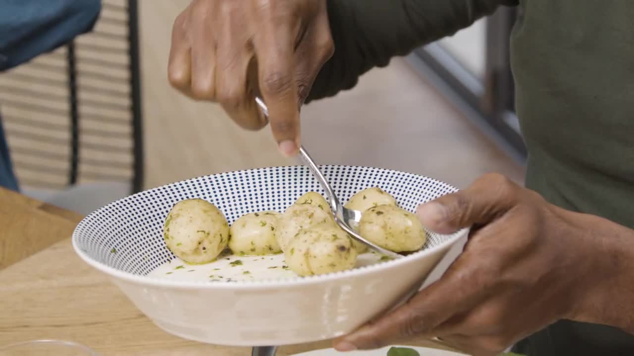 Man Plating Up Potatoes Onto His Plate During Family Dinner