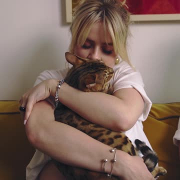 The cat and its owner share love with each other with hugs.