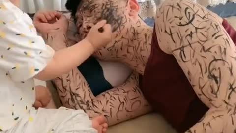 The little girl used a pen to draw on her father's body
