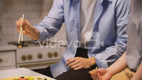 Japanese Man Picking A Piece Of Sushi With Chopsticks And Giving It To His Friend To Taste