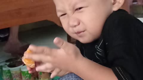 facial expression of little boy eating orange