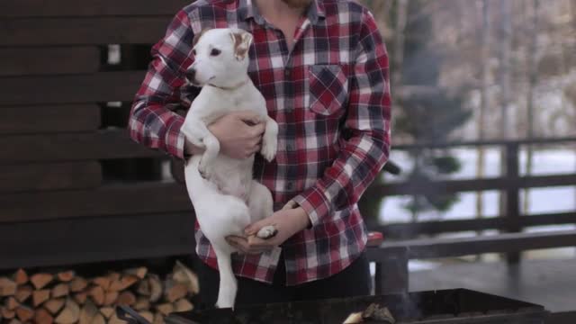 man with a puppy in his arms at the grill