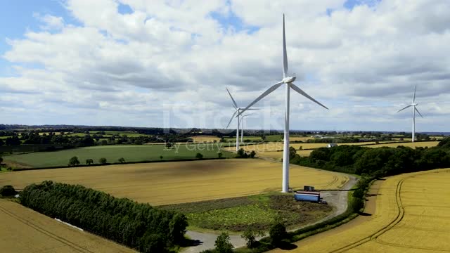 Drone shot moving towards wind turbines across windy field stock video