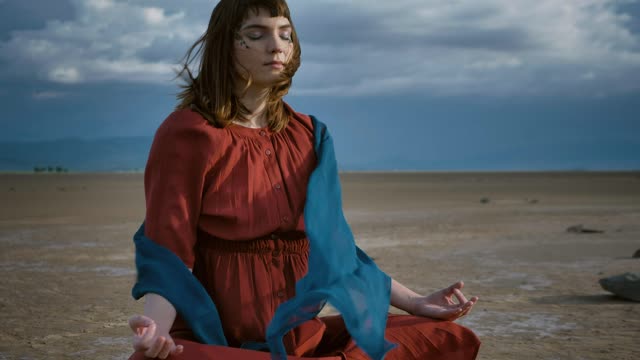 Girl meditating under the wind in the desert