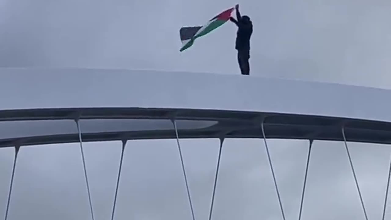 Activist fly the Palestinian flag over the top of the Hulme Arch Bridge In Manchester, Britain