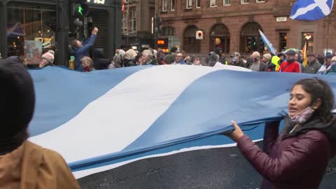 Handheld Shot of Climate Change Protesters Marching Through Glasgow with a Giant Scottish Flag