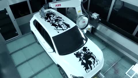 A robot paints art on a car