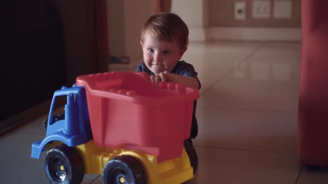 A boy playing with his plastic toy truck