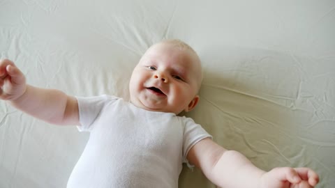 New baby boy laughing on bed