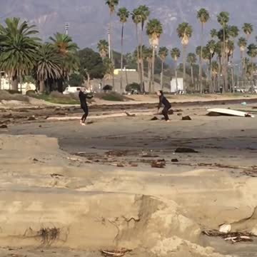Two people tossing ball back and forth at the beach