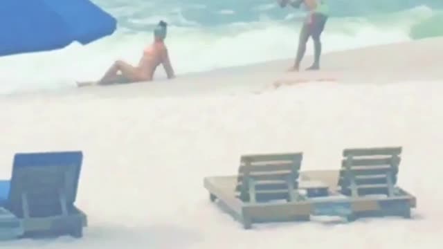 Two girls on beach taking pictures with narrator