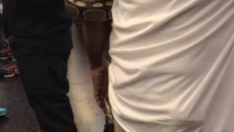 Man in white holding snake in arm on subway