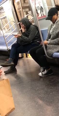 Hoodie guy looking at phone picks own booger and eats it on subway