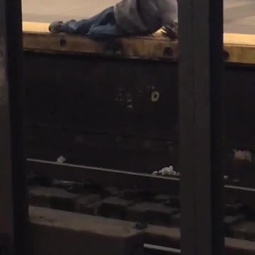 Man lays at the edge of subway station platform
