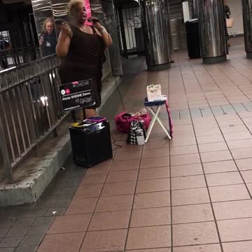 Woman with fan sings song in subway