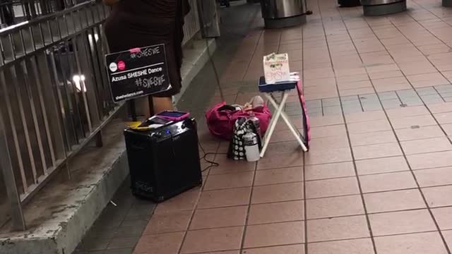 Woman with fan sings song in subway