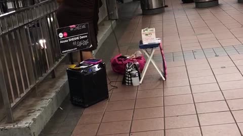 Woman with fan sings song in subway