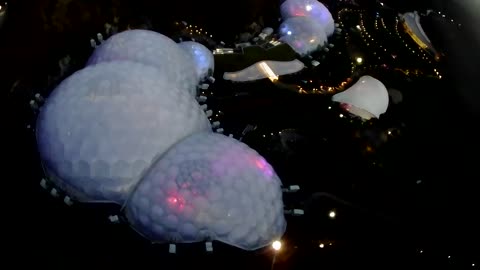 Eden Project biomes lit up, orchard and fallow field. Drone footage.