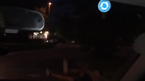 Guy in grey shirt skateboarding next to car falls down