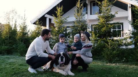 Happy family playing with their big dog near the house in nature