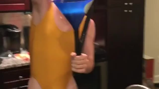 Man in yellow swimsuit drinks from blue beer bong
