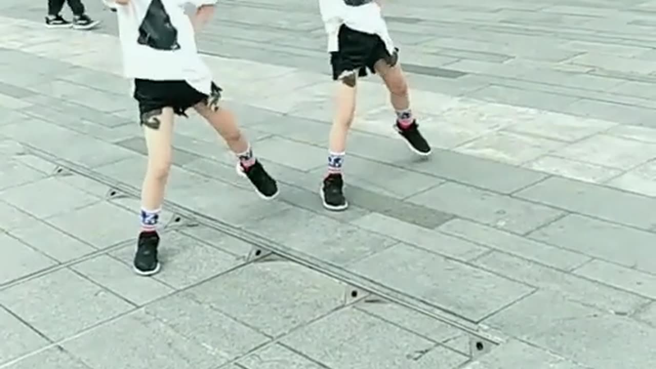 Two children are dancing in the street