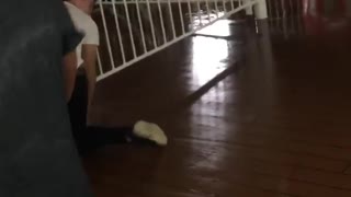 Guy runs through door way and slides on wood floors into white fence