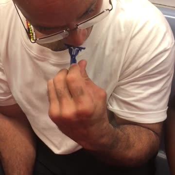 Man in white shirt uses blue razor to shave