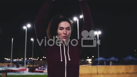 Sportive Curly Girl Stretching And Rotating Arms In The Park At Night 3