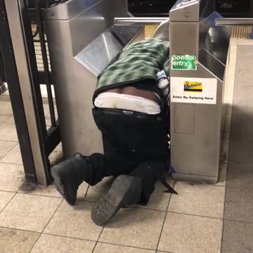 Drunk guy kneeling on floor at subway turnstile