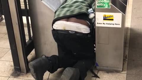 Drunk guy kneeling on floor at subway turnstile