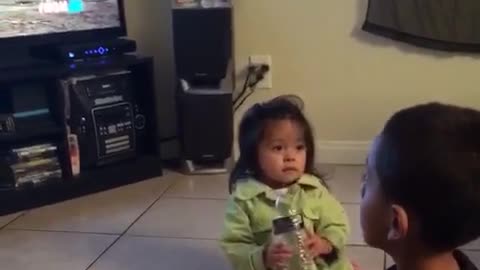 Kid in green shirt throws water bottle at kid in black shirts face