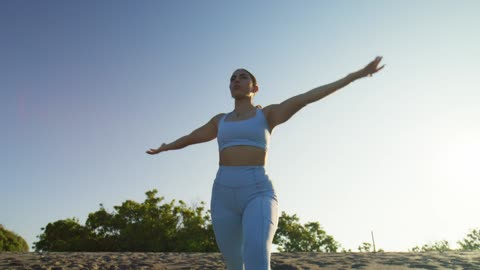 Woman practicing yoga on a sunny beach