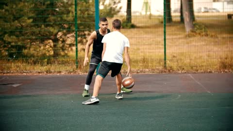Two men playing basketball in a park